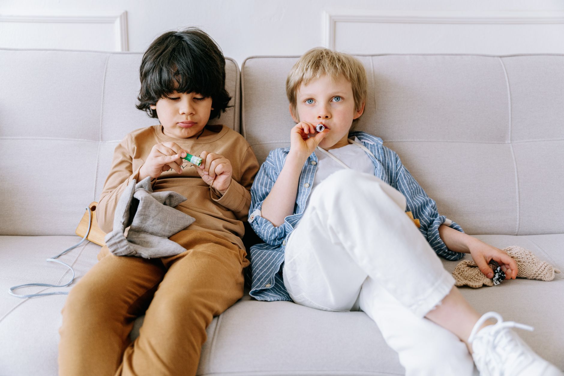 Two children relaxing on a couch, enjoying a quiet moment together indoors.