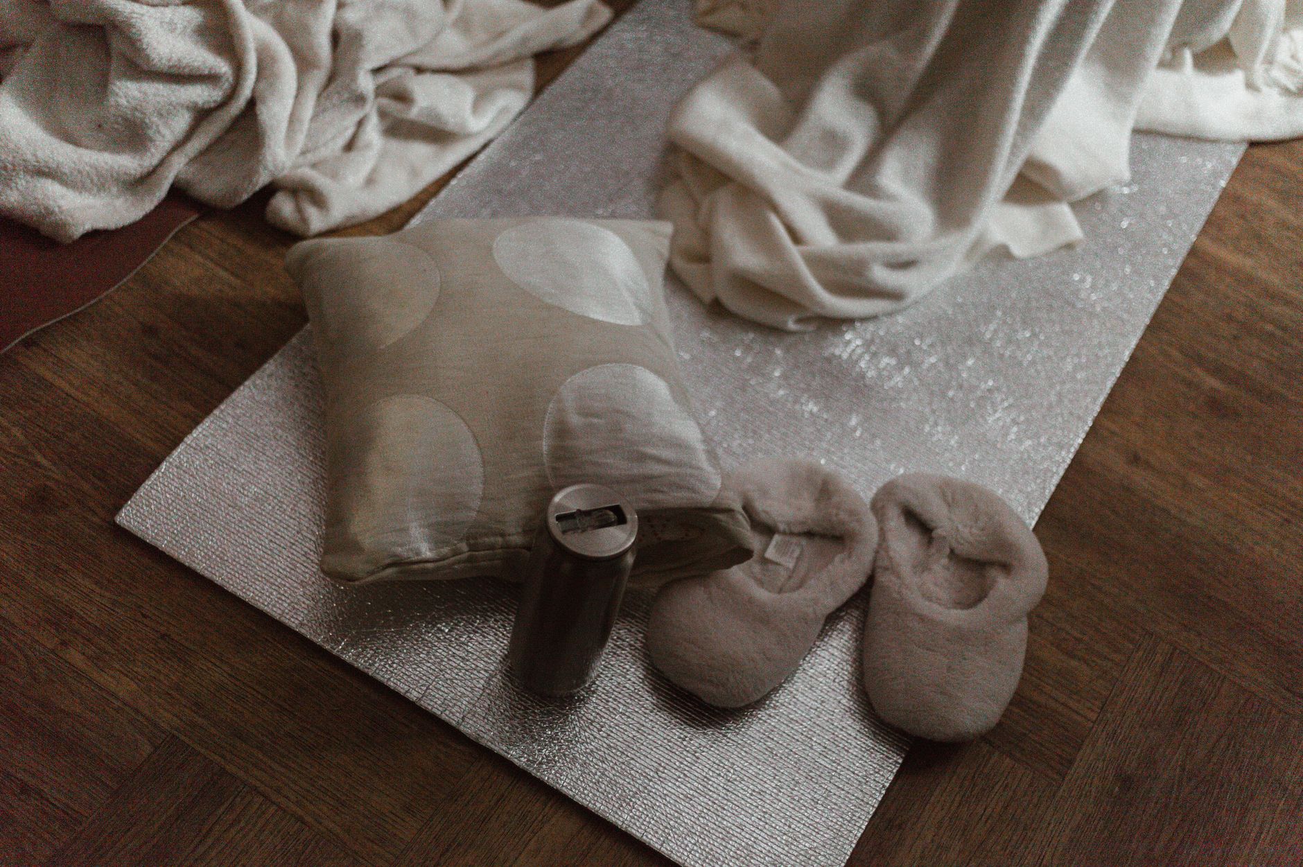 Warm and inviting indoor scene featuring slippers, a pillow, and stylish decor on a wooden floor.