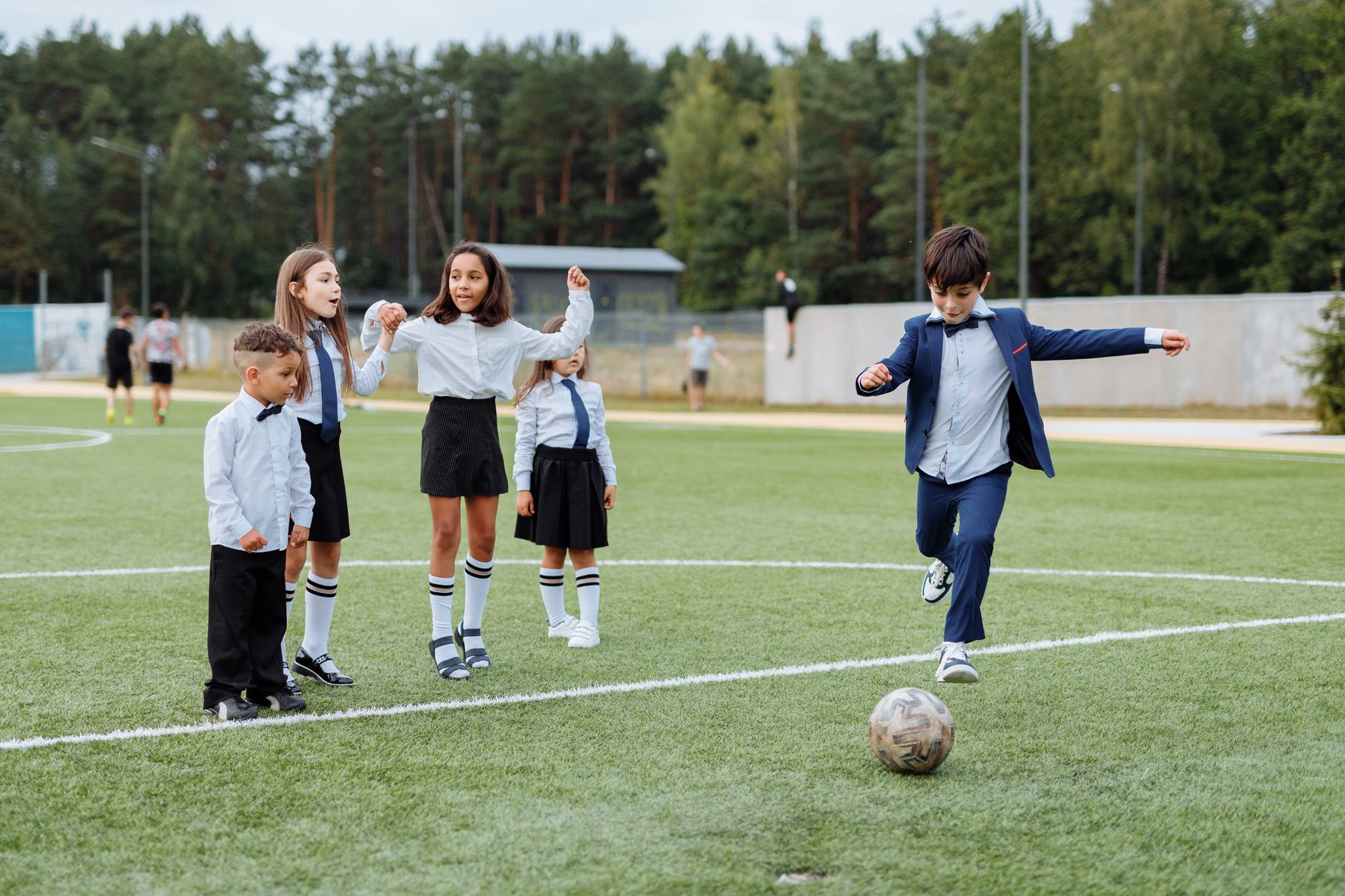 Group of children in uniforms enjoying a soccer game outdoors.