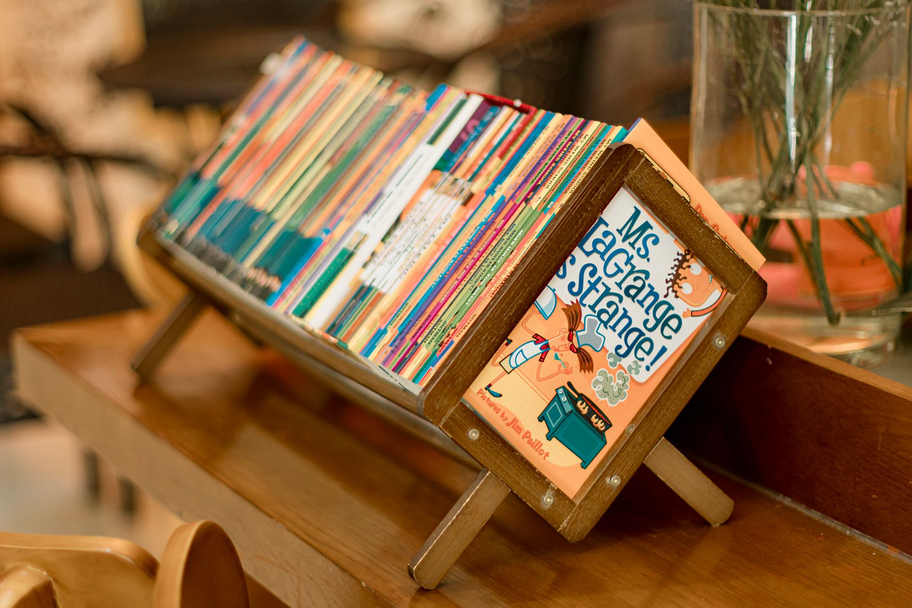 A vibrant collection of children's books on a wooden stand indoors.