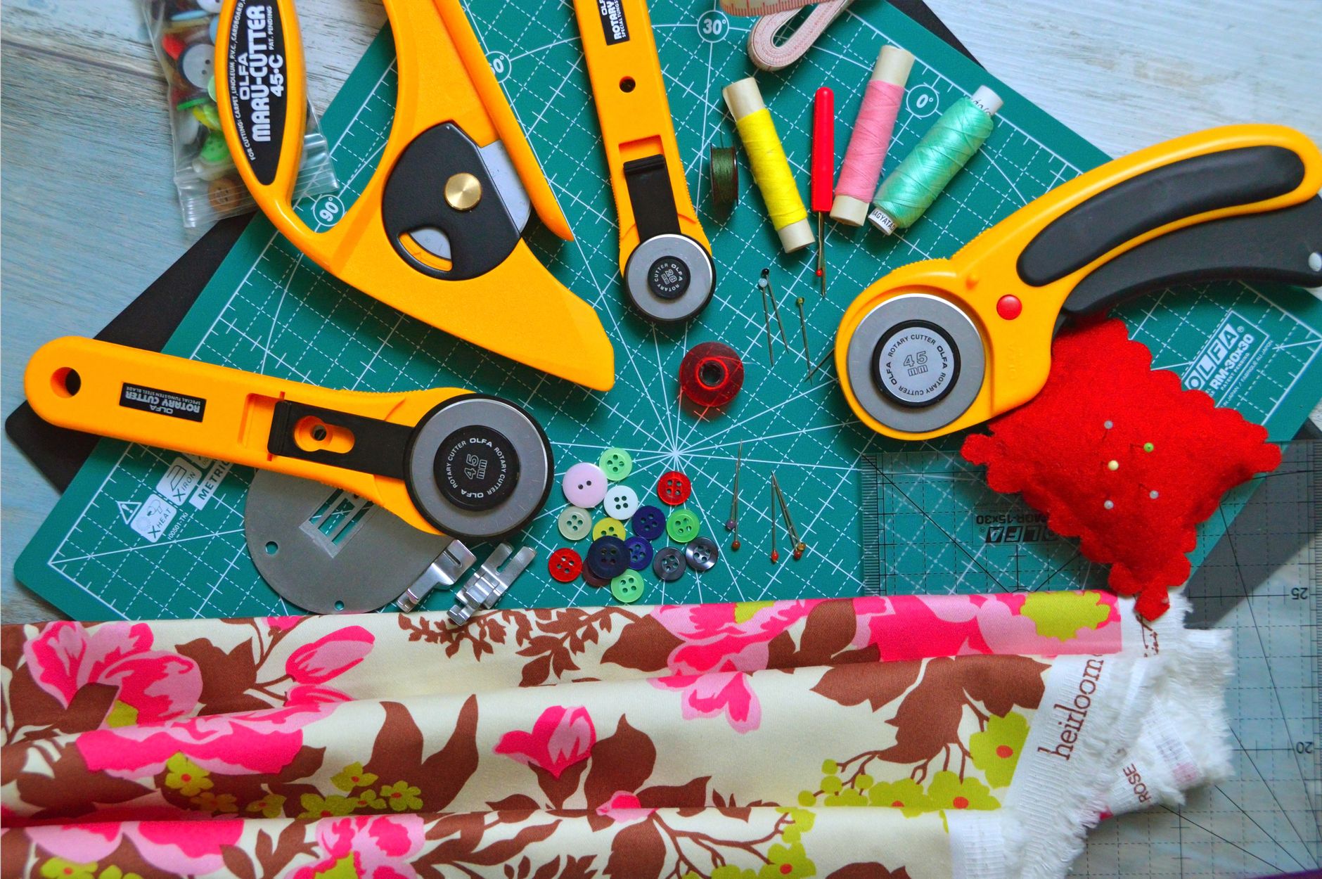 A collection of sewing tools and fabrics spread out on a green cutting mat, ideal for craft enthusiasts.
