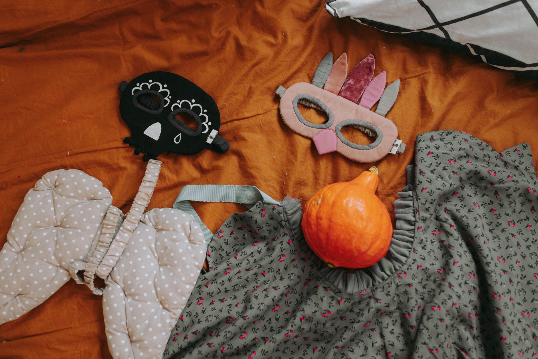 A collection of playful Halloween costumes and pumpkin on a vibrant background.