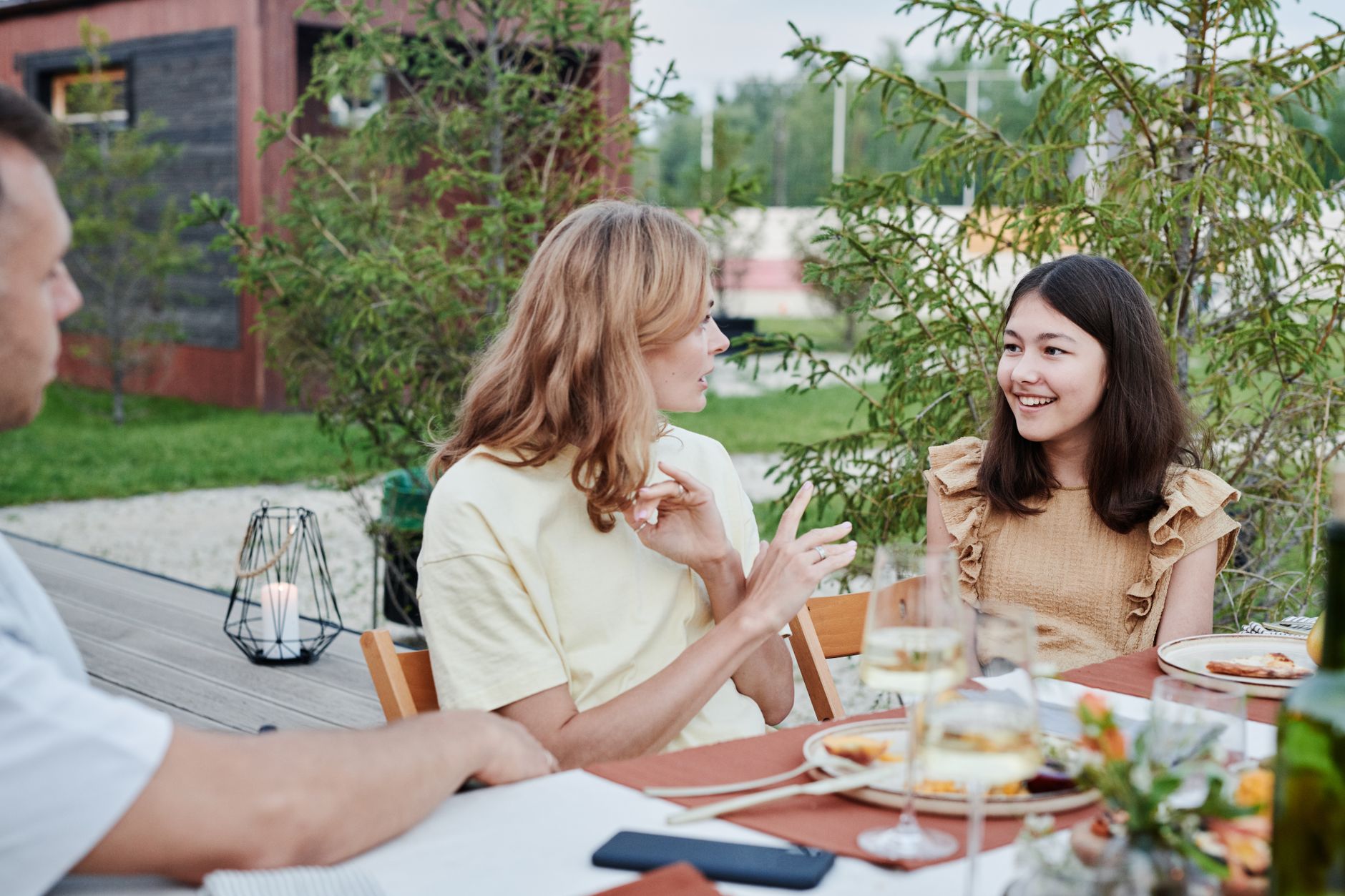 Family gathered outdoors for a lively dinner conversation on a warm day.