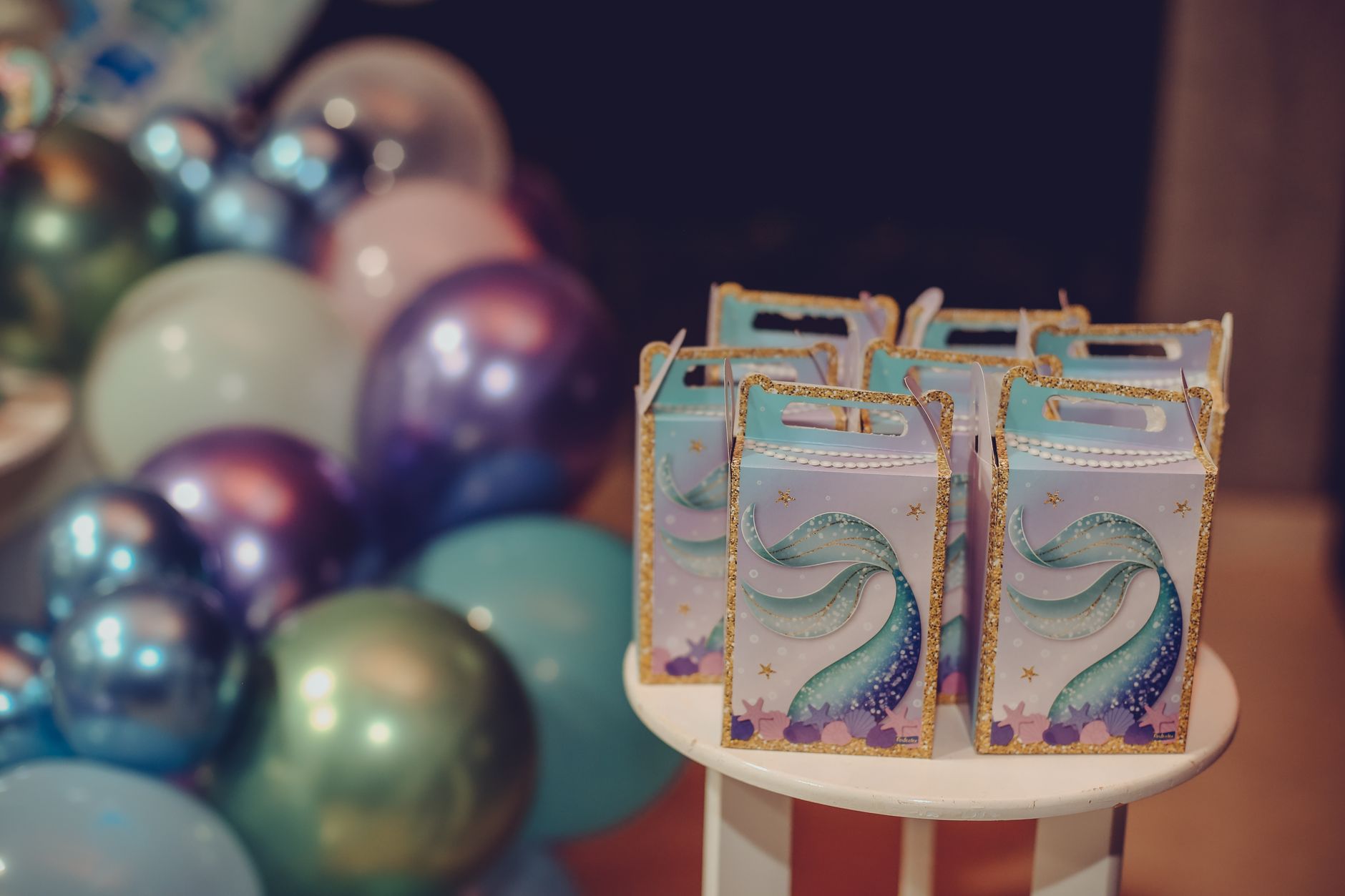 Vibrant mermaid-themed gift boxes and balloons for festive celebrations.