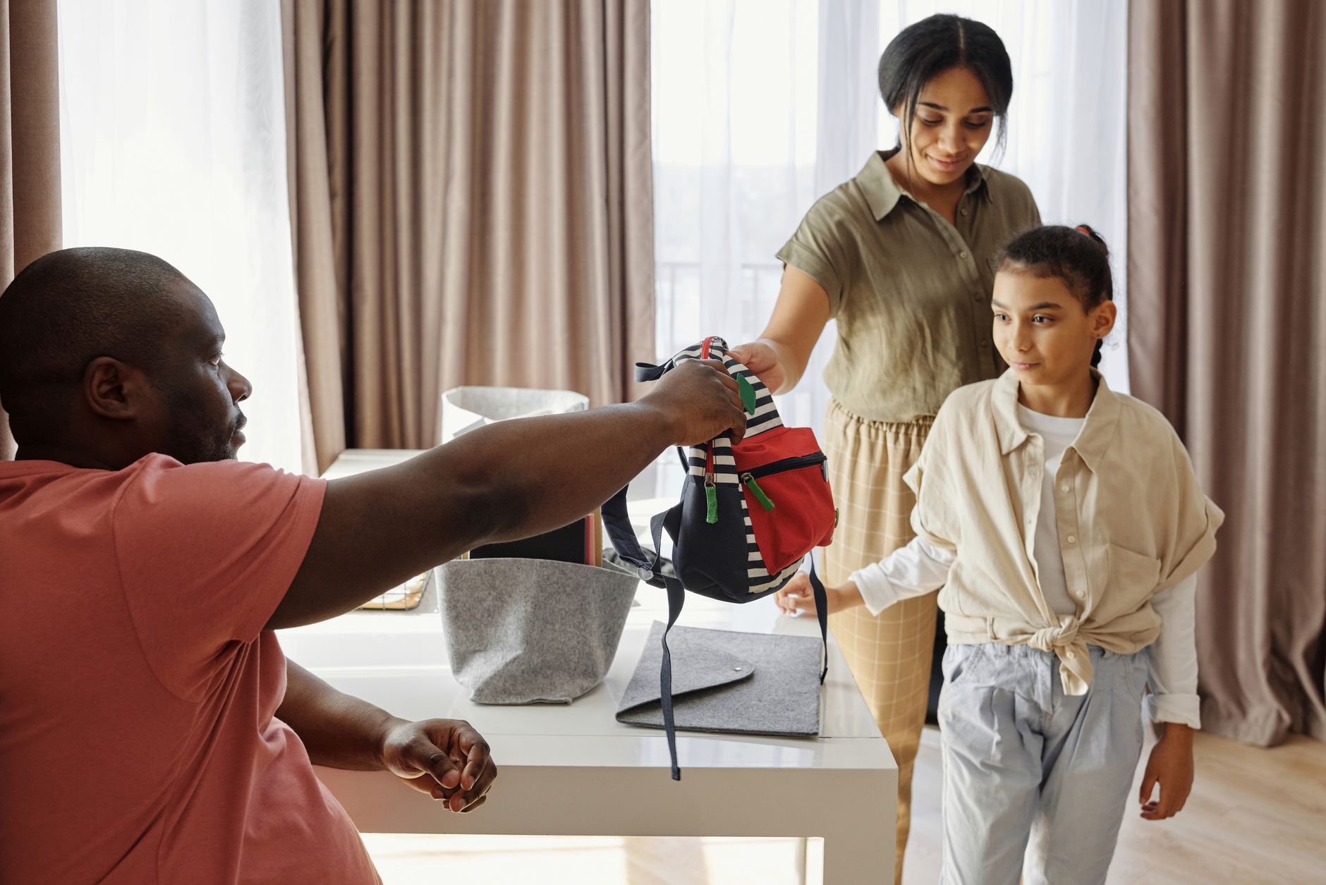 Family helping child get ready for school in a cozy indoor setting.