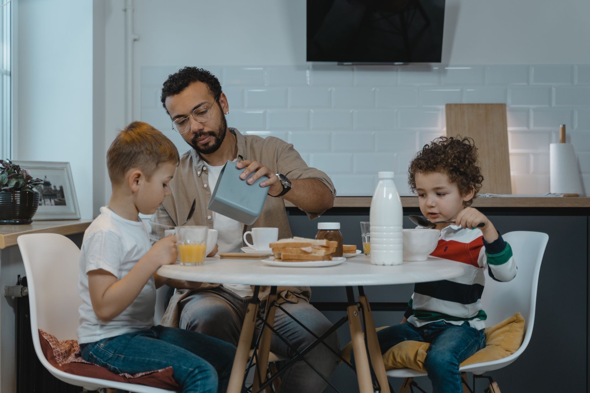 Father and sons enjoying breakfast together at a modern kitchen table.