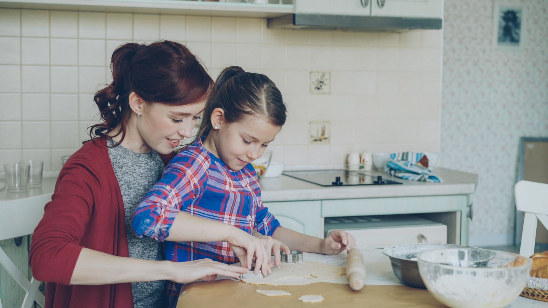 Mother and daughter enjoying baking cookies at home. Quality family time in the kitchen.
